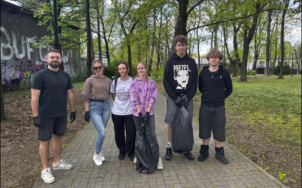 A group of young volunteers after a cleanup action with collected bags of waste.
