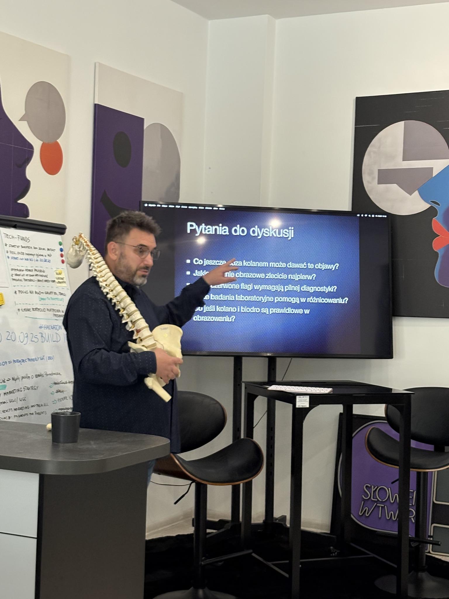 A facilitator with a spine model discusses discussion questions during a health workshop.