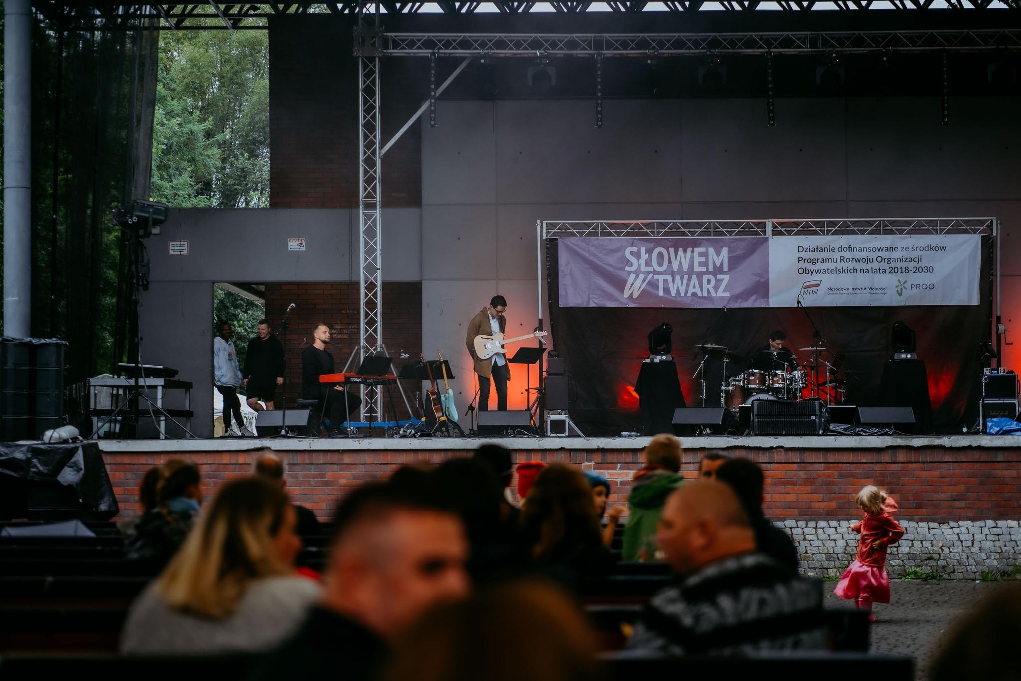 The audience sits under a tent and applauds the concert during the event.