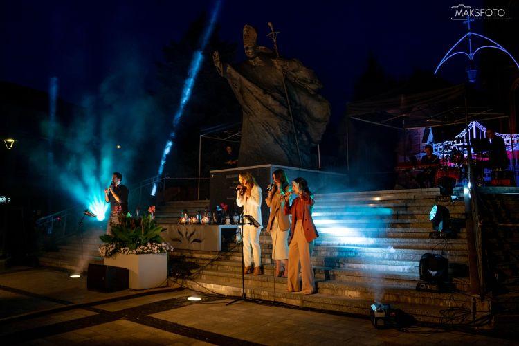 Audience watching the outdoor concert "Sent in the Peace of Christ" at dusk.